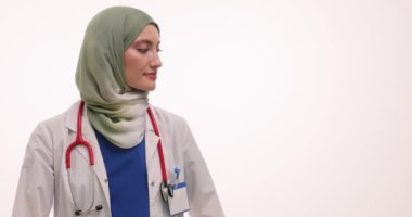 Beyaz arka planda elleri olan tesettürlü Müslüman kadın doktor. Steteskoplu neşeli kadın terapist tıbbi malzeme sunan jestler kullanır.