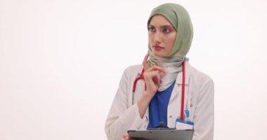 Tesettürlü düşünceli kadın doktor elinde beyaz hakkında tıbbi geçmişi olan bir dosya tutuyor. Müslüman kadın doktor, ilham vermek için işaret parmağını kaldırdı