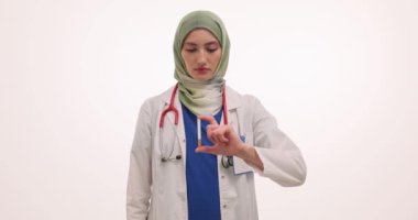 Müslüman kadın doktor sigaranın el hareketini durdurduğunu gösteriyor. Türbanlı kadın doktor, hastaya zararlı alışkanlık risklerini hatırlatıyor