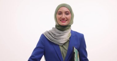 Başörtülü iş kadını beyaz arka planda iyi bir jest gösteriyor. Güzel gülüşlü kendine güvenen Müslüman kadın elinde kağıtlarla onayını veriyor.