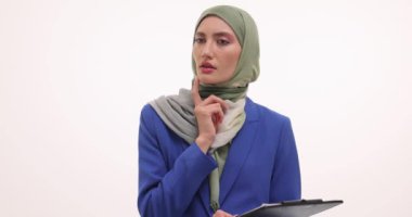 Düşünceli yüz ifadesi olan tesettürlü Müslüman bir kadın beyaz pano tutuyor. Genç bir kadın beklenmeyen bir fikir olduğunu göstermek için işaret parmağını kaldırıyor.