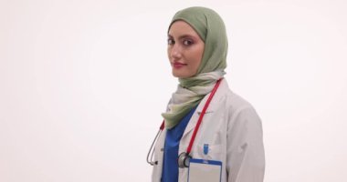 Tesettürlü gülümseyen Müslüman doktor beyaz arka planda poz veriyor. Steteskoplu kadın doktor hastanede başarılı bir kariyeri olduğunu ifade etti