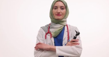 Başörtüsü takan kendine güvenen doktor beyaz arka planda otoskop kolları tutuyor. Mutlu Müslüman terapist klinikteki randevusuna hazırlanıyor