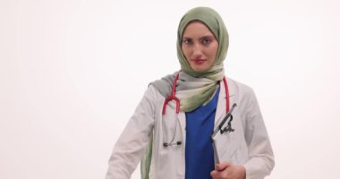 Tesettürlü üzgün kadın doktor beyazlara karşı baş parmak işareti gösteriyor. Steteskopu ve panosu olan Müslüman doktor hayal kırıklığını dile getirdi