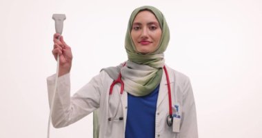 Türbanlı kadın doktor ultrason dönüştürücü tutuyor ve görüntüleri tarıyor. Müslüman kadın terapist randevudaki müdahalesiz prosedürlerin aşamalarını açıklıyor