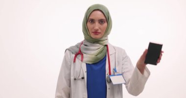 Başörtülü Müslüman kadın doktor, akıllı telefonun beyaza baş parmak hareketi yaptığını gösteriyor. Üniformalı kadın terapist bana görme sağlığını hatırlatıyor.