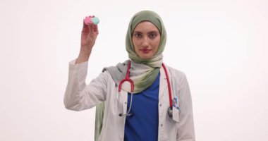 Müslüman kadın doktor lensleri ve gözlükleri beyaza karşı gösteriyor. Türbanlı kadın göz doktoru hastaya çeşitli çözümler sunuyor