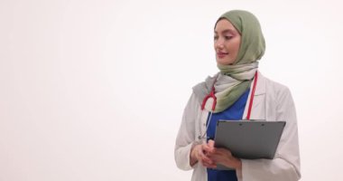 Tesettürdeki kadın doktor beyazlar hakkında bilgi veriyor. Hastanede elinde panoyla Müslüman kadınlar işaret ediyor