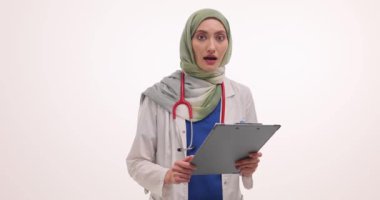 Tesettürlü kadın doktor elinde beyaz hakkında tıbbi rapor tutuyor. Müslüman kadın doktor başarılı tedavi sonuçlarıyla sevinçlerini dile getirdi