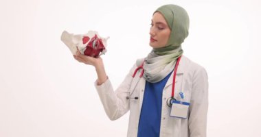 Tesettürlü kadın doktor leğen kemiklerinin randevuda olduğunu gösteriyor. Müslüman jinekologlar genç hastalara hastanede randevuda açıklama yapıyor