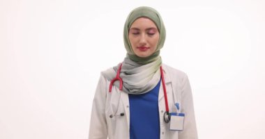 Tesettürlü kadın doktor glukometre ve bir bardak şekeri beyaza karşı gösteriyor. Müslüman kadın doktor klinikteki şeker hastaları için sağlıksız ürün gösteriyor