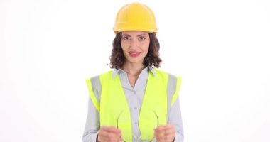 Kadın inşaat işçisi beyaz arka plana güvenlik gözlüğü takıyor. Kendine güvenen kadın mühendis inşaat alanında yavaş çekimde çalışmaya hazırlanıyor.