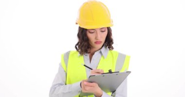 Miğferli kadın mimar panoya not alıyor. Üniformalı kadın işçi, beyaz arka planda projeler yapmak için örnekler hazırlıyor.