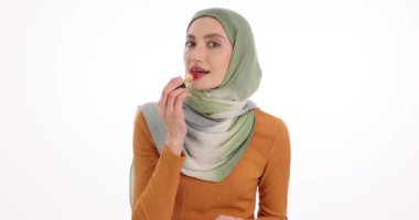 Arap kadın güzellik blogcusu beyaz arka plana kırmızı ruj sürüyor. Türbanlı kadın video dersinde lüks makyaj malzemesi kullanıyor.