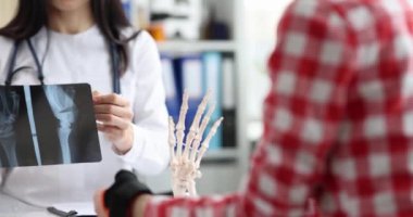 Doktor yaralı kollu bir hastayla konuşur ve röntgen çeker. El yaralanmaları ve kırık kavramı