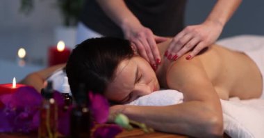 Kadınlar spa merkezini mumların yanında yatarken seviyorlar. Sırt masajı konsepti