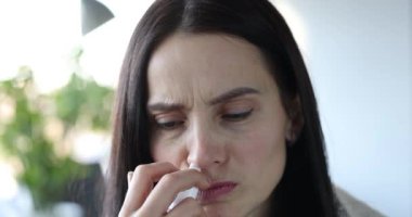 Woman with severe runny nose holds medicine spray into nose in hand. Allergy and seasonal disease runny nose concept