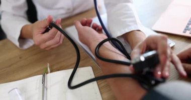 Kardiyolog doktor klinikte tonometresi olan erkek hastaya kan basıncını ölçüyor. Atardamar hipertansiyonu ve kalp sorunları teşhisi
