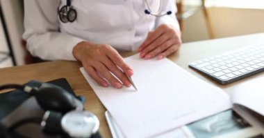Doktor elleri hastanın elektrokardiyogramına bakıyor. Yardım kardiyoterapisti nabız ölçümleri hakkında kardiyolojik inceleme yapar
