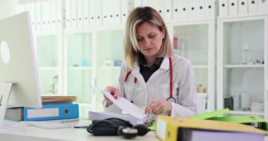 Pratisyen hekim klinikte oturur ve önemli belgeler ve dosyalarla çalışır. Tıbbi kayıtlar ve hasta geçmişi arşivi