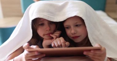 Dijital tabletle battaniyenin altında iki kız bebek. Çocukluk rüyası çevrimiçi video oyunu konsepti