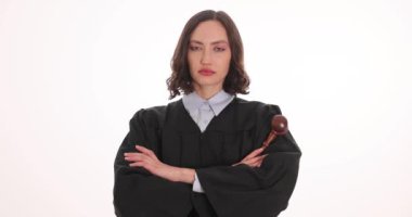 Siyah cüppeli kadın yargıç beyaz arka planda tokmak çapraz kolları tutuyor. Kadın hakem profesyonel çevrede otoriteyi somutlaştırıyor