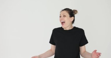 Saçlı çörekli genç bir kadın ağzı açık, neşe saçıyor. Gündelik kıyafetli neşeli bayan mutluluğu haykıran elleriyle yüzüne dokunuyor.