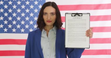 Kendine güvenen iş kadını, Amerikan bayrağına karşı kontrat imzaladı ve onayladı. Hoş gülüşü olan kadın girişimci kendine güveni yansıtır
