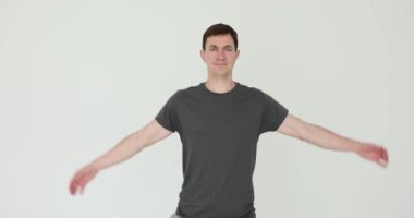 Spor kıyafetli adam, beyaz arka planda kol ve omuz egzersizlerinin çeşitliliğini gösteriyor. Sporcu dayanıklılık ve esneklik gösteriyor