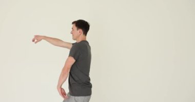 Neşeli esmer adam beyaz arka planda el sallayarak dans ediyor. Orta yaşlı erkek koreografi hareketleri yaparken eğleniyor. Ağır çekimde ilham veren dansçı