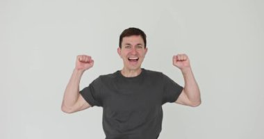 Mutlu adam beyaz arka planda gülümseyen kollarını kaldırır. Adam sevinç ve heyecan saçar kutlama anını yakalar ağır çekimde zafer kazanır