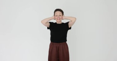 Kadın kulaklarını elleriyle kapatıyor ve beyaz arka planda konuşmak istemiyor. Kadın, yavaş çekim sırasında çatışma durumundan kaçınır