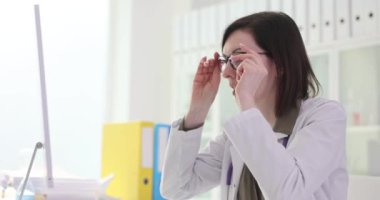 Kadın hastanedeki bilgisayar ekranına bakarak gözlükleri çıkarıyor. Esmer aile doktoru monitörden beklenmeyen verilere şaşırarak tepki veriyor.