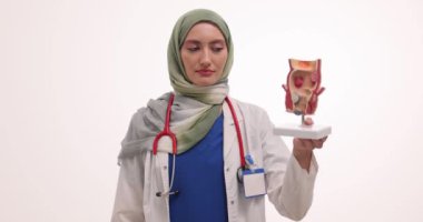 Kadın doktor prostat bezinin modelini ve beyazın üstüne ilacın su toplamasını gösteriyor. Türbanlı Müslüman kadın doktor tedavi seçeneklerini yavaş çekimde açıklıyor