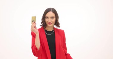 Kırmızı ceketli genç bir kadın beyaz arka planda alışveriş torbaları ve kredi kartı tutuyor. Esmer kadın mutluluğu alışverişlerle yayıyor.