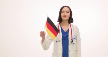 Mutlu kadın doktor beyaz arka planda Alman bayrağı sallıyor. Üniformalı kadın doktor, başka bir ülkeden meslektaşlarını karşıladı.