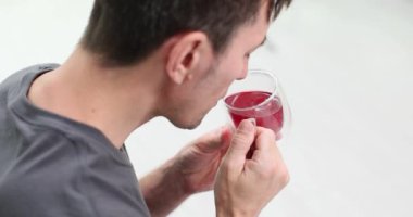 Adam kırmızı bardakta kırmızı içkinin tadını alıyor. Kokudan ve ağızda kalan tattan hoşlanıyor. Kahverengi saçlı ciddi bir adam sıcak bitki çayına üflüyor.