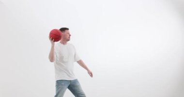 Konsantre sporcu, beyaz arka planda atış teknikleri uyguluyor. Adam yaklaşan oyun için atış becerilerini geliştirmeye çalışıyor.