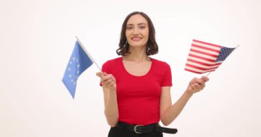 Kadın, beyaz arka planda Amerikan bayrağı ve Avrupa Birliği bayrağını tutuyor. Kadın, Atlantik ötesi ilişkilere ağır çekimde destek gösteriyor
