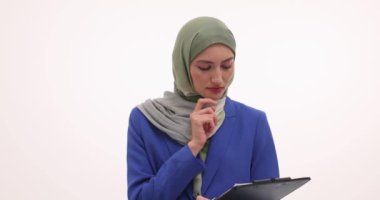 Tesettürlü genç iş kadını elini çeneye koymayı düşünüyor. Başörtülü bayan girişimci beyaz arka planda yeni bir fikir olduğunu belirterek parmağını kaldırdı