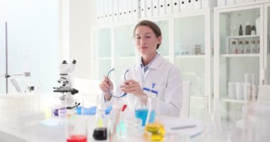Üniformalı kadın bilim adamı laboratuardaki iş yerinde koruyucu gözlük takıyor. Kadın teknisyen klinikte kimyasal araştırmaya hazırlanıyor.