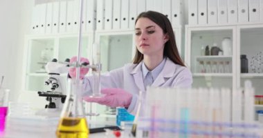 Beyaz cüppeli kadın bilim adamı modern laboratuardaki iş yerinde burette ayarlıyor. Odaklanmış kadın teknisyen araştırma yapmaya hazırlanıyor.