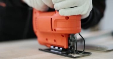 İnşaat işçisi, tahta kiriş üzerinde işaretli hat boyunca elektrikli yapboz kullanıyor. Profesyonel müteahhit, ahşap tahtayı kenar çizgisine getirmek için incelikle keser.