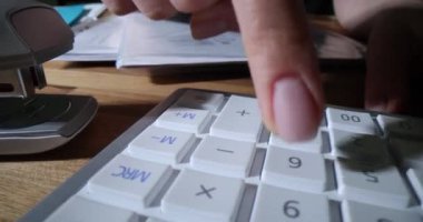 Muhasebeci masada oturur ve hesap makinesindeki tuşlara basar. Profesyonel çalışan, şirketin kar ve zararlarını özenle hesaplıyor