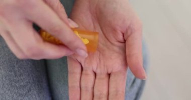 Kadın tedavi için ilaç kutusundan ilaç alıyor. Kadın, sağlık yönetiminin ağırdan almasının önemini vurgulamak için avuç içine ilaç koyar