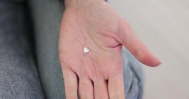 Kadının elinde sağlık hizmetlerini sembolize eden kalp şeklinde haplar var. Bayan, bütünsel sağlığa bağlılık konusunda avuç içi takviyesi sunuyor.