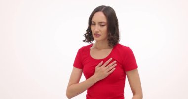 Genç bir kadın elini göğsüne koyar ve beyaz arka planda güçlü bir acı hisseder. Esmer kadın kalp krizinin acı veren belirtilerinden muzdarip.