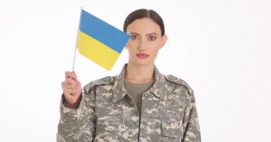 Cesur bir Ukraynalı asker ulusal bayrağı gururla gösteriyor, zorluklara karşı vatanseverliği ve dayanıklılığı simgeliyor.