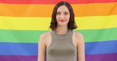 Kendinden emin bir birey canlı ve renkli bir gökkuşağı bayrağının önünde gururla durur.