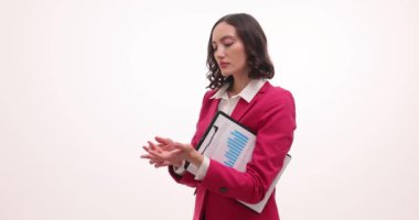 Kadın elinde dosyalarla pano tutuyor ve parmaklarıyla el hareketlerini sayıyor. Kırmızı ceketli kadın çalışanlar önemli görevleri ağır çekimde sıraladı.